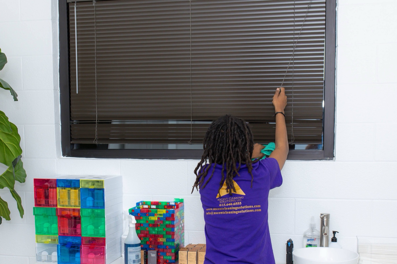 Ascent Cleaning Solutions team member in branded uniform cleaning blinds in a Nashville daycare